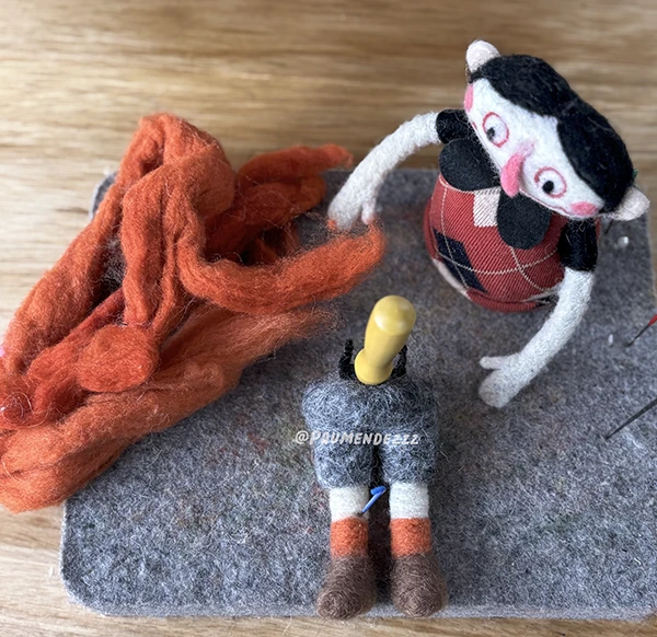 Two felt figures lying on a wool base