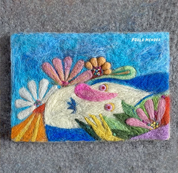 Felt picture of a creature among flowers on a blue background